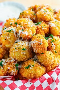 a basket filled with fried food covered in parmesan cheese and parsley sprinkled on top