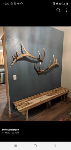 a wooden bench sitting in front of a wall with antlers on it