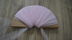 a pink fan sitting on top of a wooden table next to a white netted cloth