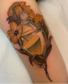 a woman's leg with an old fashion perfume bottle and flowers tattoo on it