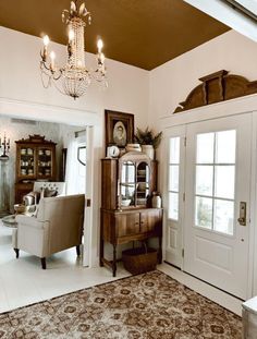 a living room filled with furniture and a chandelier hanging from the ceiling over a doorway