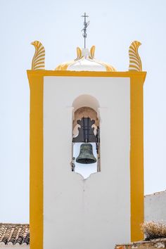 a bell tower with a cross on top and a window in the wall above it