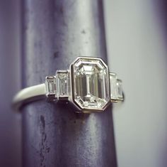 an emerald and diamond ring sitting on top of a pole