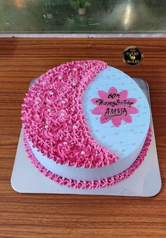 a birthday cake decorated with pink sprinkles on top of a wooden table