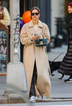 a woman walking down the street while holding a cell phone