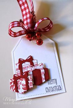 a christmas ornament with red and white gift boxes on it, attached to a tag