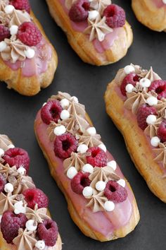 raspberry and cream filled pastry with white chocolate toppings on black surface next to other pastries