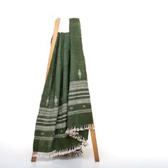 a green and white towel is on a wooden stand with two pieces of cloth hanging from it's sides