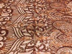 an intricately designed table cloth with gold sequins and brown lace on it