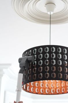 a person holding up a light fixture in the middle of a room with white walls