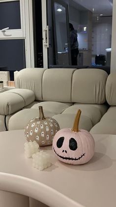 two pumpkins sitting on top of a table in front of a couch and window