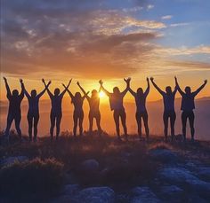 a group of people standing on top of a mountain with their arms in the air