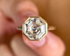 a close up of a person's hand holding a ring with a diamond in it