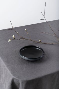 a black plate sitting on top of a table next to a twig tree branch