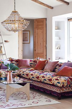 a living room filled with lots of furniture and a chandelier hanging from the ceiling