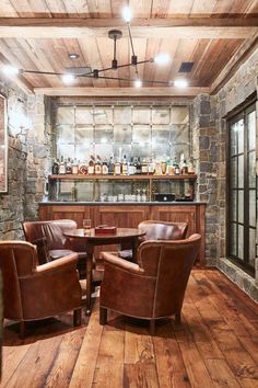 a room with chairs, tables and bottles on the bar area in front of it