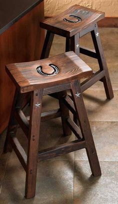 two wooden stools sitting next to each other on a tile floor in front of a counter