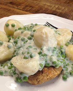 a white plate topped with potatoes and peas