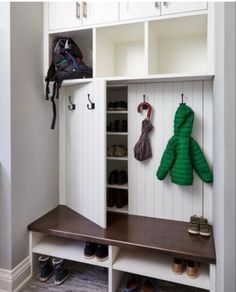 a coat rack with two coats hanging on it's sides and some shoes underneath