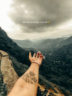 a person's arm with tattoos on it and mountains in the background