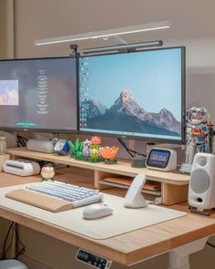 two computer monitors sitting on top of a wooden desk