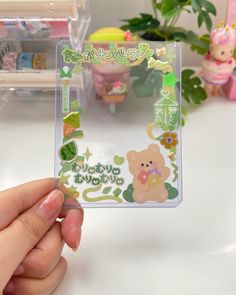 someone is holding up a clear card with some stickers on it and there are other toys in the background