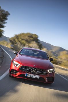 a red mercedes cla driving down the road