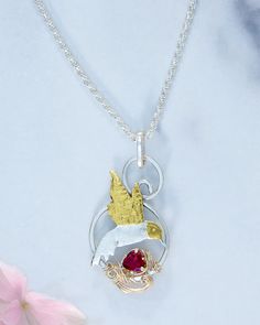 Hummingbirds are always a joy to watch! These charming, tiny acrobats always brighten my day. I design and meticulously craft each hummingbird piece by hand to capture these birds' delicate grace and beauty in flight. The combination of sterling silver, 23K gold accents, and a genuine garnet adds natural elegance to this handmade piece. It is a perfect accessory for nature lovers to add to their collection. Each necklace is a testament to my passion for creating beautiful, timeless jewelry that brings joy to those who wear it. More Information. Sterling Silver, fine silver, 23K gold Pendant is approximately 1 5/8" tall and 1" wide 18" long sterling silver diamond cut rope chain with lobster claw clasp Genuine garnet Individually handmade with subtle design variations Gold Plated Gemstone Necklace Hummingbird, Hummingbird Necklace, Handmade Jewelry Earrings, Hanging Jewelry, Brings Joy, I Design, Timeless Jewelry, In Flight, Hand Made Jewelry