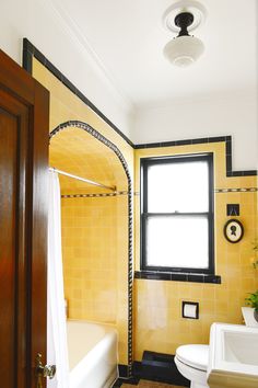 a bathroom with yellow tiles and black trim