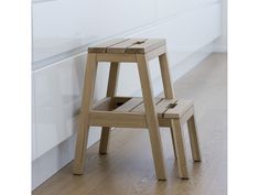 two wooden stools sitting next to each other on a hard wood floor in front of a white wall