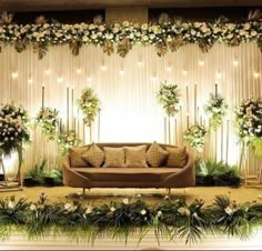 a couch sitting in front of a wall with flowers and greenery