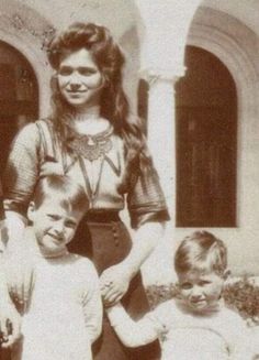 an old black and white photo of a woman standing with two young children in front of a building