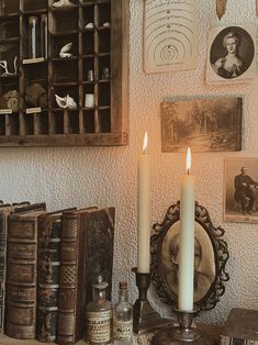 two candles sitting on top of a table next to old books and other antique items