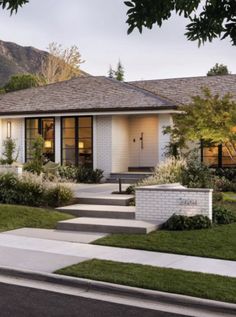 a white house with steps leading up to it's front door and grass lawn