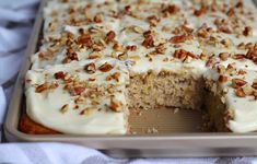 a cake with white frosting and pecans on top is cut into slices from the side