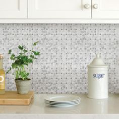 a kitchen counter with plates and cups on it, next to a canister that says sugar