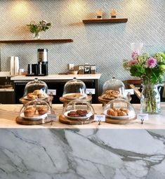 a marble counter top with pastries and flowers in vases next to the counter