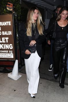 a woman in white pants and black jacket