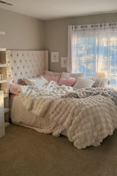 a large bed sitting in the middle of a bedroom next to a window with curtains