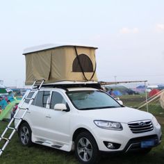 a white suv parked in the grass with a tent on top