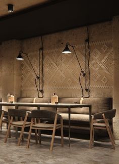 an empty restaurant with wooden tables and chairs in front of a wall that has lights on it