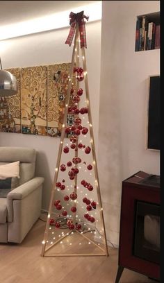 a christmas tree with ornaments and lights in the shape of a pyramid is displayed in a living room