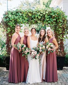 a group of women standing next to each other in front of a trellis covered archway