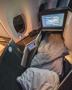 the inside of an airplane with a bed and monitor