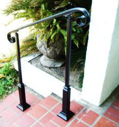 an iron hand rail on the side of a house next to a potted plant