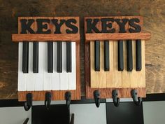 two wooden keys are attached to the wall with black and white keys on each key holder