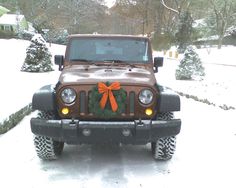 a jeep with a wreath on the front is parked in the snow near some trees