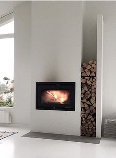 a living room with a fire place in the corner and wood stacked on the floor