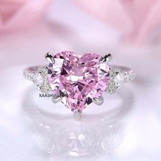 a pink heart shaped diamond ring with three diamonds around it