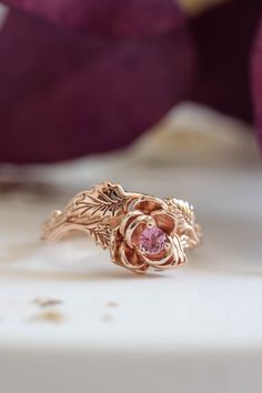 a close up of a ring on a table with purple flowers in the back ground